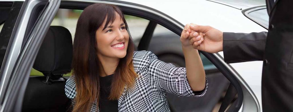 Een reiziger stapt met hulp van de chauffeur in de taxi